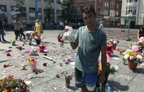 Un adolescent roman doarme in strada pentru a pazi lumanarile si florile depuse in memoria victimelor de la Manchester
