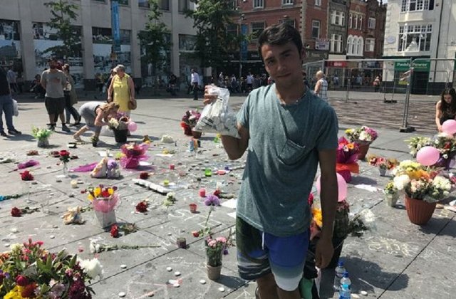 Un adolescent roman doarme in strada pentru a pazi lumanarile si florile depuse in memoria victimelor de la Manchester
