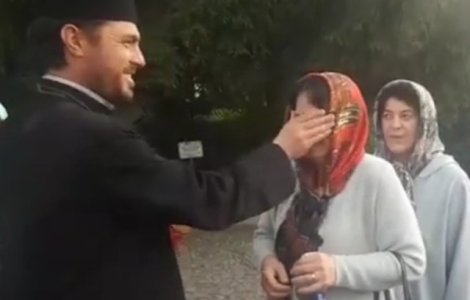 Un preot "plesneste" peste ochi credinciosii cu aghiasma, in curtea unei manastiri/ VIDEO