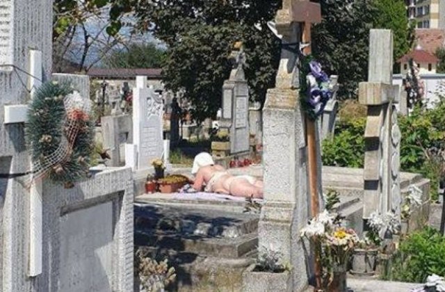 FOTO La plajă în cimitir. O femeie și-a întins pătura pe un mormânt, printre cruci și flori