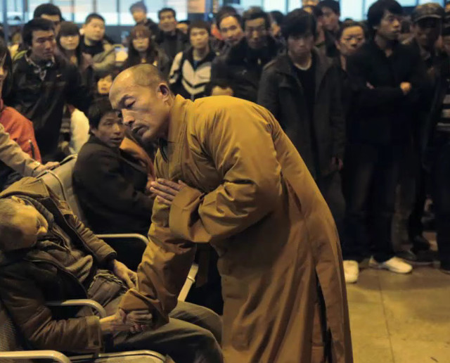 Un calugar se roaga pentru un barbat in varsta care a decedat subit in timp ce se astepta un tren in gara din Shanxi Taiyuan, China.