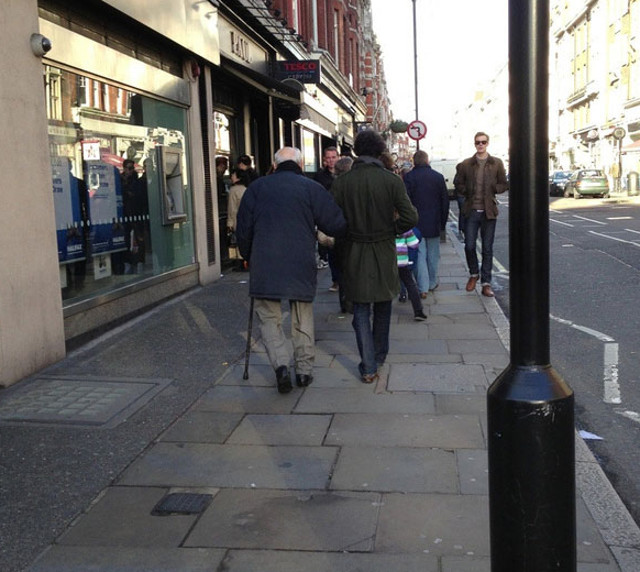 Un tanar ii ofera bratul lui unui batranel de pe strada