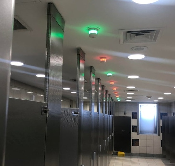 O baie publica unde poti vedea, dupa luminile de sus, ce toalete sunt ocupate